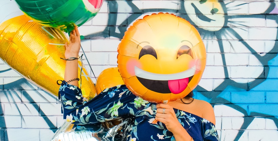 woman holding smiling emoji balloon